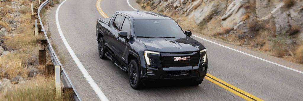 Black 2026 GMC Sierra EV driving on a mountain road
