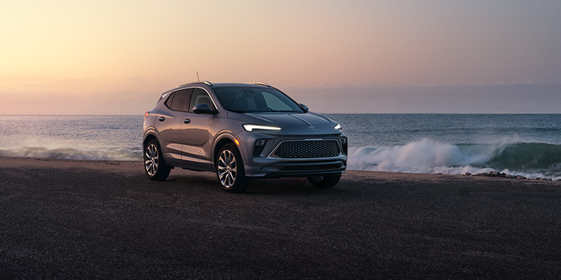 Silver Buick Encore GX on a beach at sunrise
